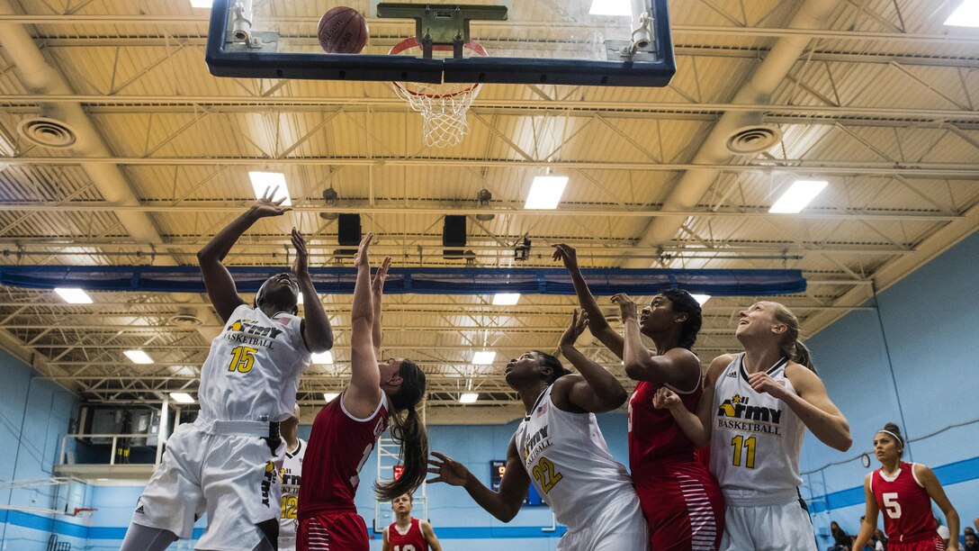 An basketball player attempts a layup as others jockey for position under the basket.