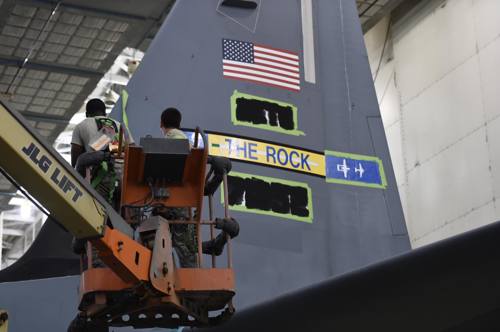 Airman paint new tail flash to tail of C-130.