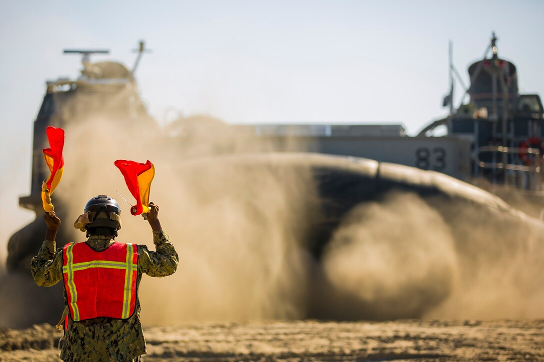 A U.S. Navy Sailor signals Landing Craft, Air Cushion 83, to embark on the amphibious assault ship USS Iwo Jima (LHD-7) as part of Composite Training Unit Exercise (COMPTUEX) at Onslow Beach, Camp Lejeune, N.C., Nov. 5, 2017. The 26th MEU is scheduled to conduct Composite Training Unit Exercise, its final pre-deployment training exercise in preparation for an upcoming deployment at sea.