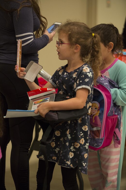 A Foster Girl Scout waits in line to fill up a donation backpack