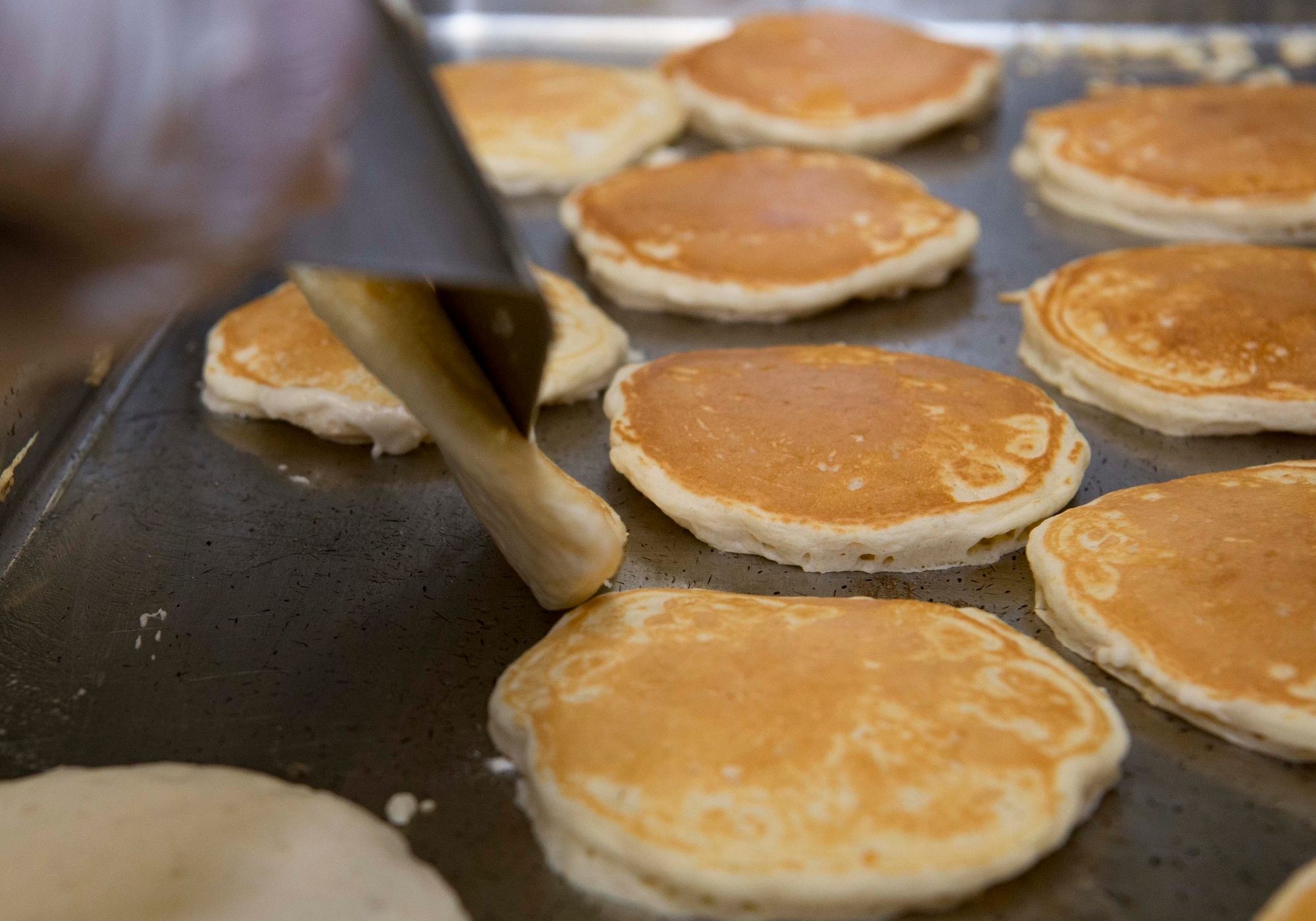 U.S. Air Force Airman 1st Class Saul Ramos-Garcia, 786th Force Support Squadron Rheinland Inn shift leader, flips pancakes on Ramstein Air Base, Germany, Nov. 3, 2017. The inn provides access to ready-made meals for Ramstein personnel living in the dorms. (U.S. Air Force photo by Senior Airman Elizabeth Baker)