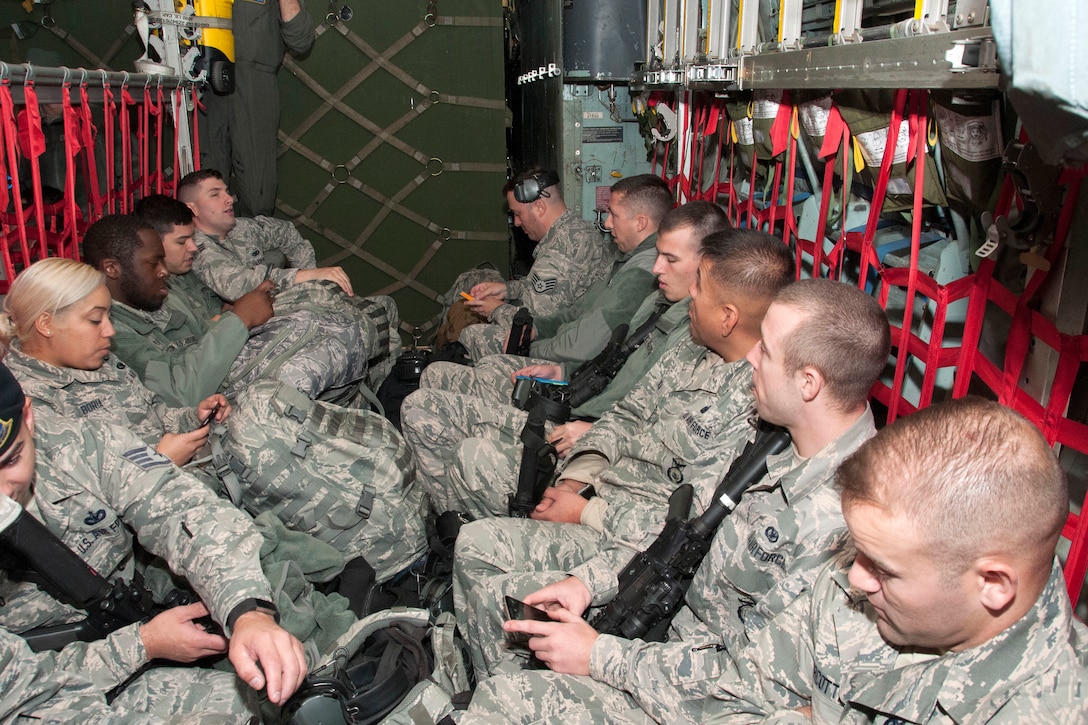 Air National Guardsmen sit in jump seats aboard a C-130 Hercules.