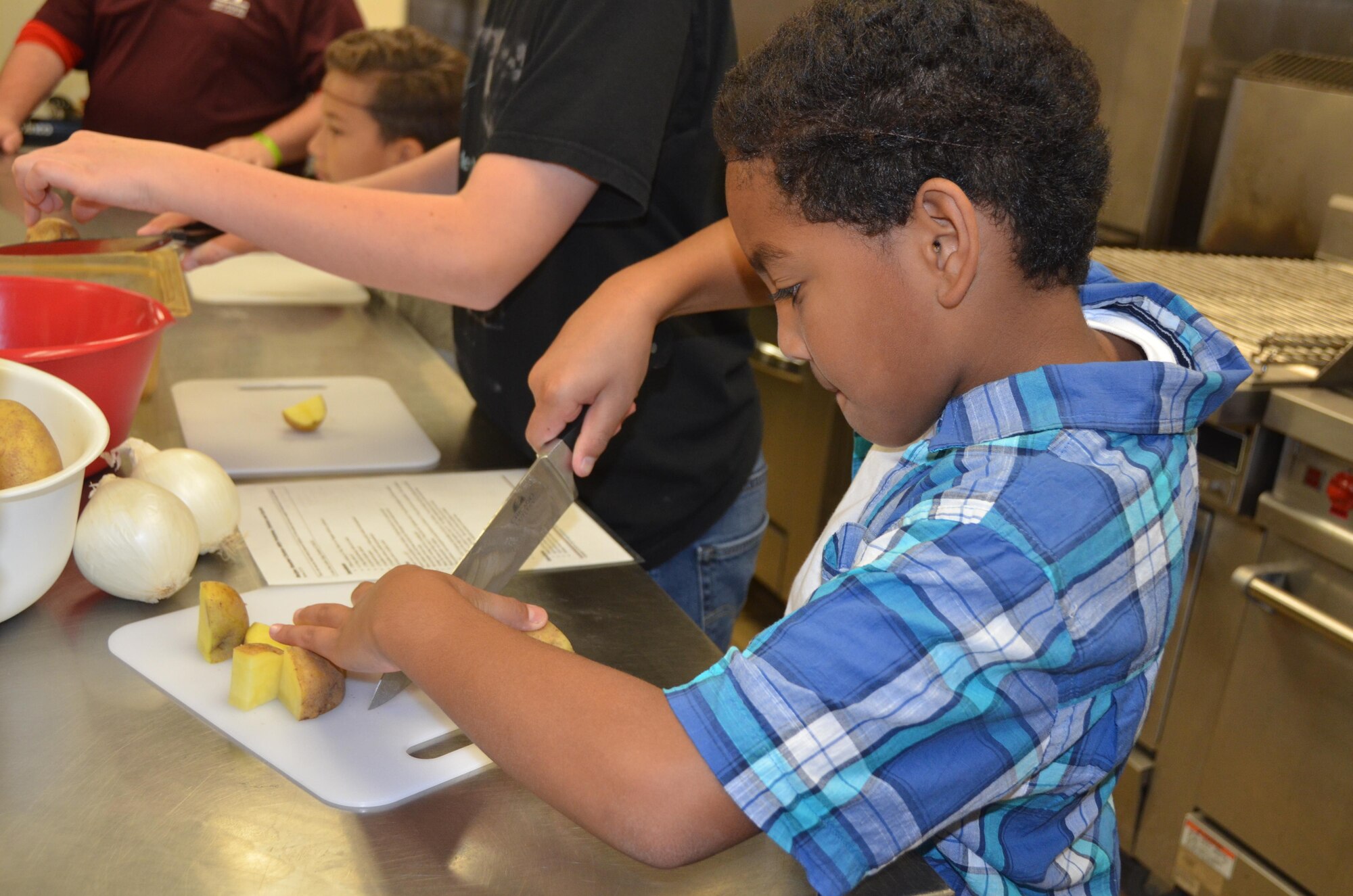 Child slices potatoes during Healthy Cooking Camp for Kids