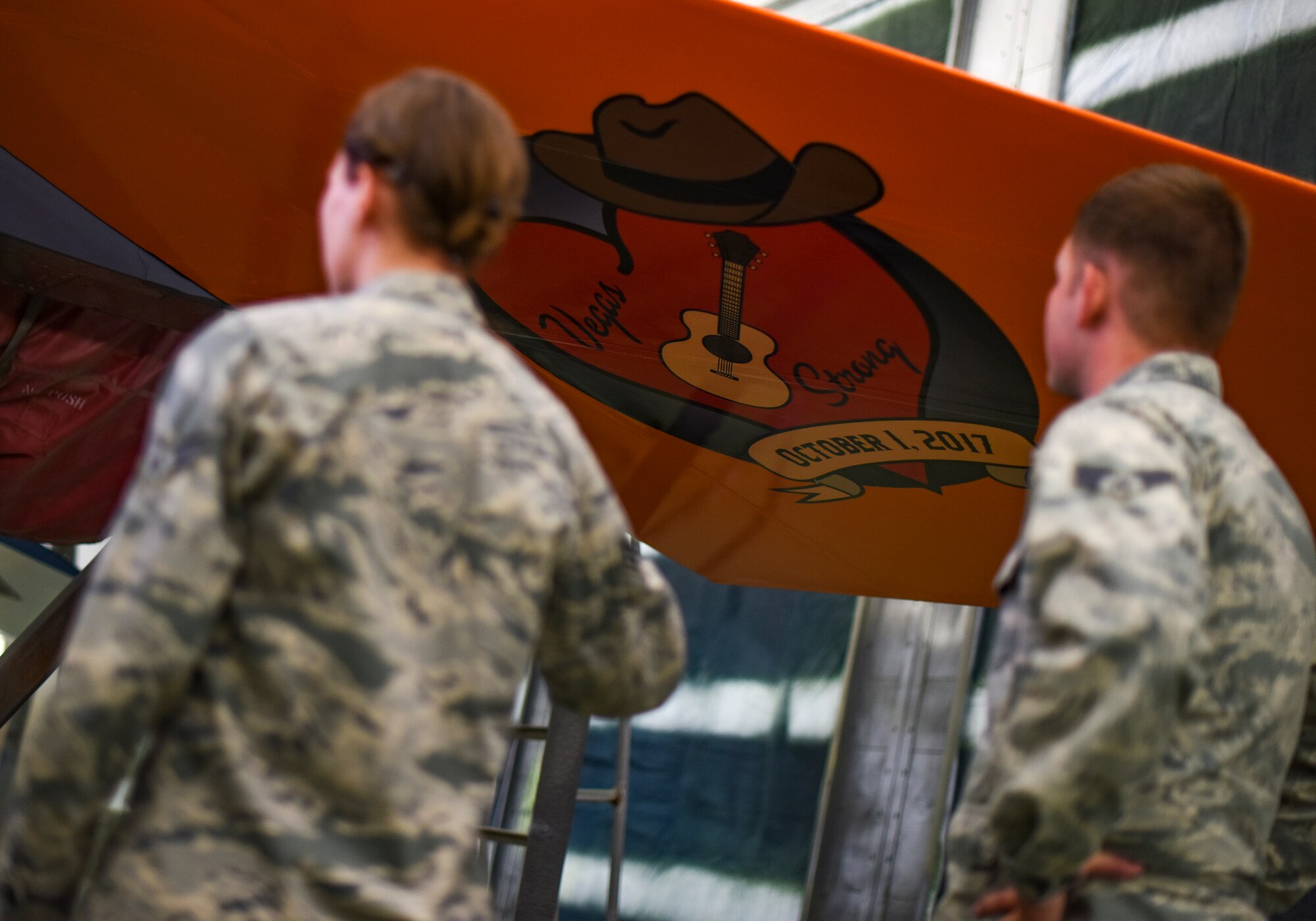 Senior Airmen Brittany Galloway and Dillon Cutlip, 57th Wing creative design team members, observe their final product on the tail of an F-15C Eagle at Nellis Air Force Base, Nevada, Nov. 1, 2017. The aircraft is being repainted to recognize the Air Force's 70th Anniversary as well as the unity between the Las Vegas community and Nellis AFB. (U.S. Air Force photo by Airman 1st Class Andrew D. Sarver/Released)