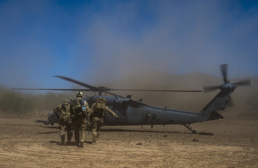 Pararescue airmen carry a patient to a helicopter.