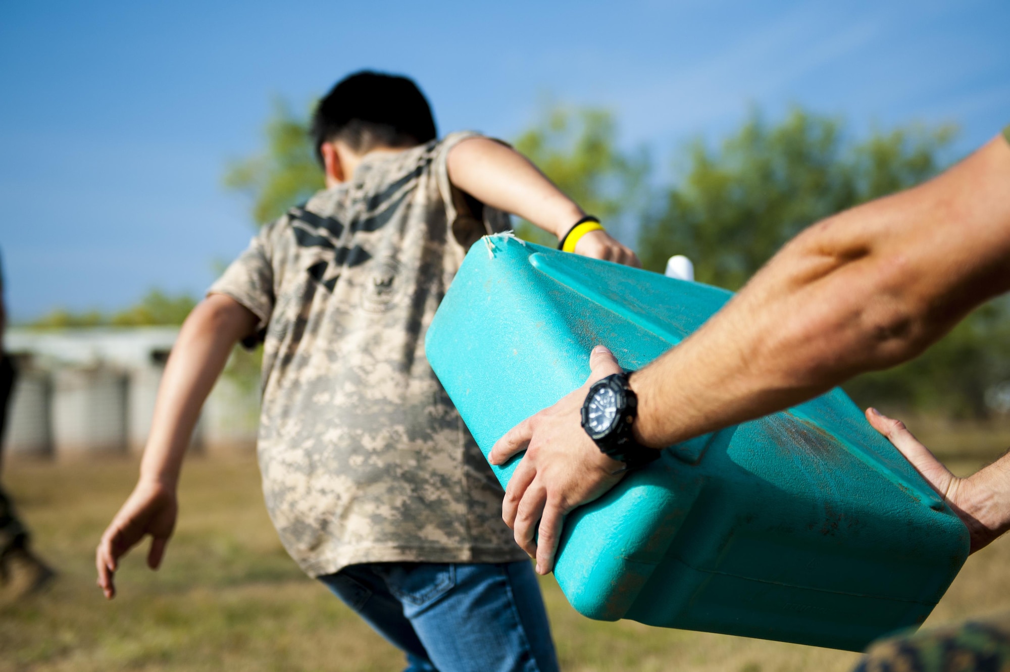 A participant of Operation Kids Investigating Deployment Services picks up a water container before running an obstacle course at the Afghan Village on Goodfellow Air Force Base, Texas, Nov. 4, 2017. During Operation KIDS, volunteer children interacted in simulated deployed environments. (U.S. Air Force photo by Senior Airman Scott Jackson/Released)