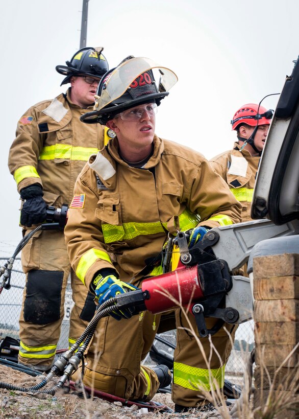 An Army National Guard firefighter cuts into a vehicle.