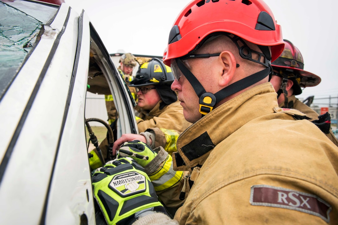 Army Guard firefighters try to enter a damaged vehicle.