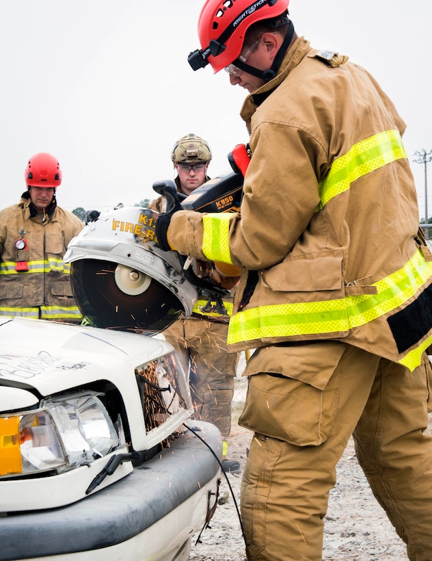 Army Guard firefighter cuts into a wrecked vehicle.