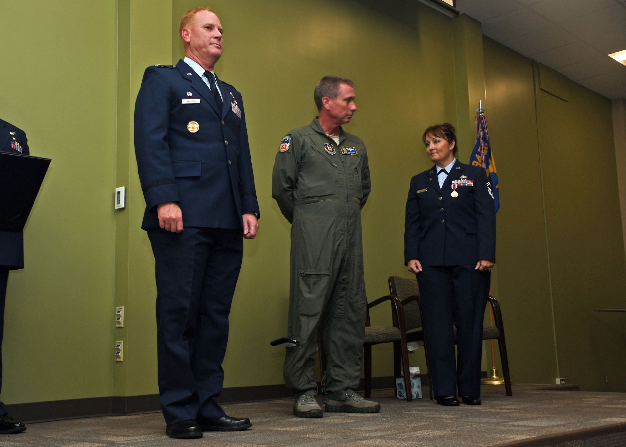 From left, Col. James Kellogg, 94th Airlift Wing commander; Master Sgt. Todd Owens, 700th Airlift Squadron loadmaster; and Senior Master Sgt. Donna Bridges, 94th AW law office superintendent; stand on stage shortly before Kellogg presented Owens with a spouse certificate of appreciation at Bridges' retirement ceremony Nov. 4, 2017. The certificate was presented to Owens, Bridges' husband, to show the wing's appreciation for his support throughout Bridges' 34-year career. (U.S. Air Force photo/Staff Sgt. Miles Wilson)