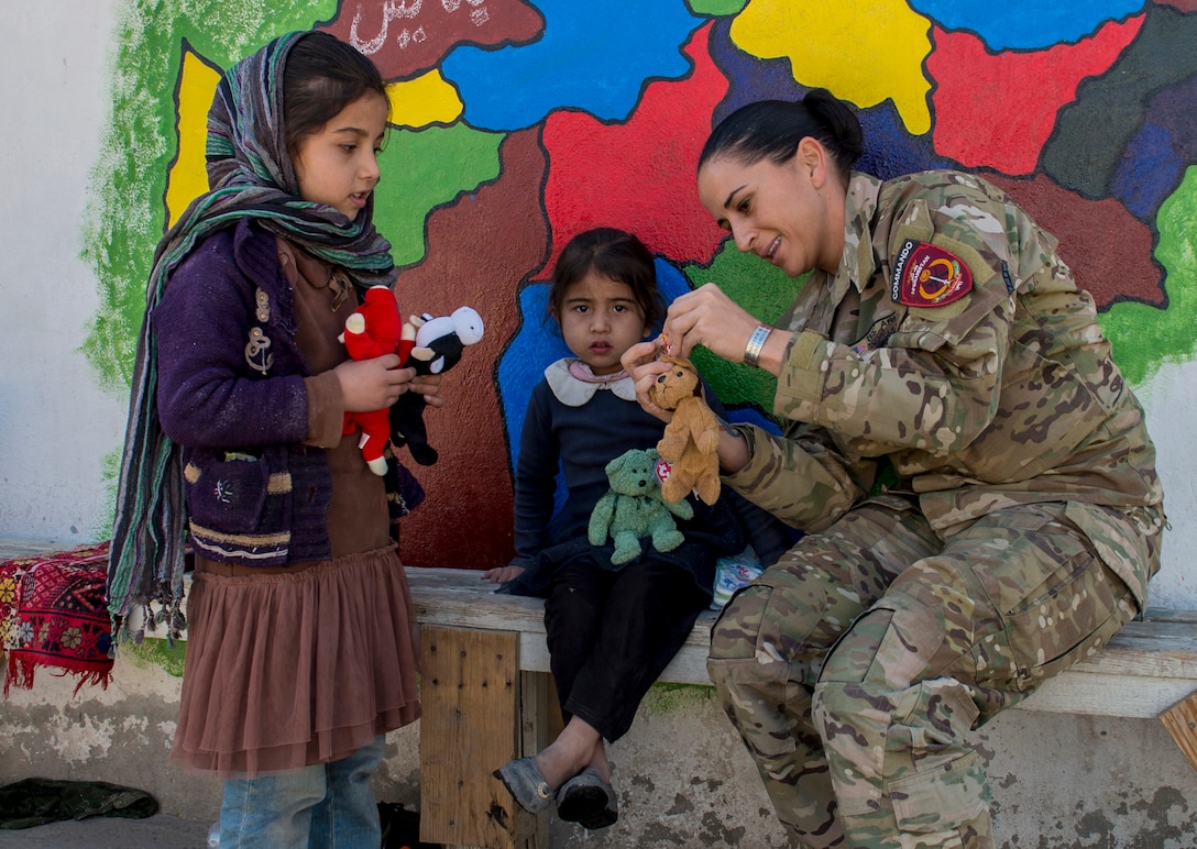 Chief Warrant Officer 3 Kaylan Harrington, Afghan National Army Special Operations Advisory Group mentor, assists with the Afghan Commandos' routine essential items distribution at the Camp Commando medical clinic, Kabul, Nov. 6, 2017. All items provided to the Afghan woman and children are donated from local villages
