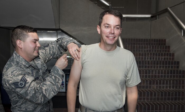 U.S. Air Force Staff Sgt. Jacob Radford, left, 628th Aerospace Medical Squadron allergy and immunizations technician, administers the annual flu shot to U.S. Air Force Col. Jeffrey W. Nelson, right, 628th Air Base Wing commander, during a mobile flu line in the Joint Base Charleston Headquarters Building Nov. 7, 2017.