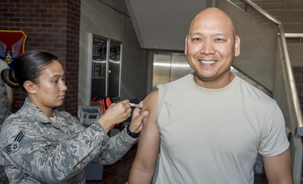 U.S. Air Force Senior Airman Cheree Voto, left, 628th Aerospace Medical Squadron immunization backup technician, administers the annual flu shot to U.S. Air Force Col. Jimmy Canlas, right, 437th Airlift Wing commander, during a mobile flu line in the Joint Base Charleston Headquarters Building Nov. 7, 2017.