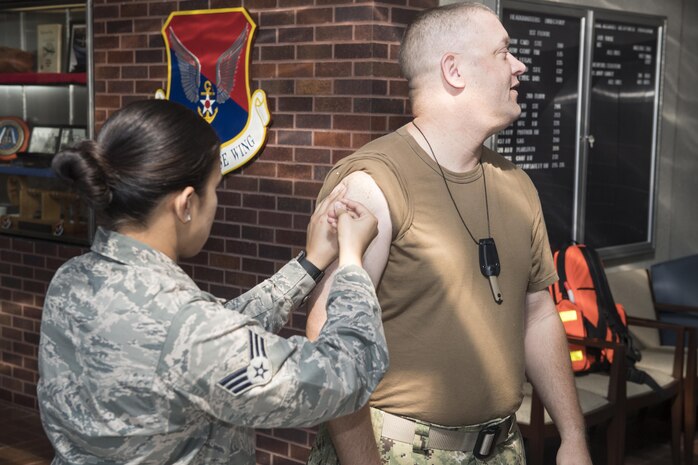 U.S. Air Force Senior Airman Cheree Voto, left, 628th Aerospace Medical Squadron immunization backup technician, administers the annual flu shot to U.S. Navy Command Master Chief Petty Officer Asa Worcester, right, 628th Air Base Wing command master chief, during a mobile flu line in the Joint Base Charleston Headquarters Building Nov. 7, 2017.