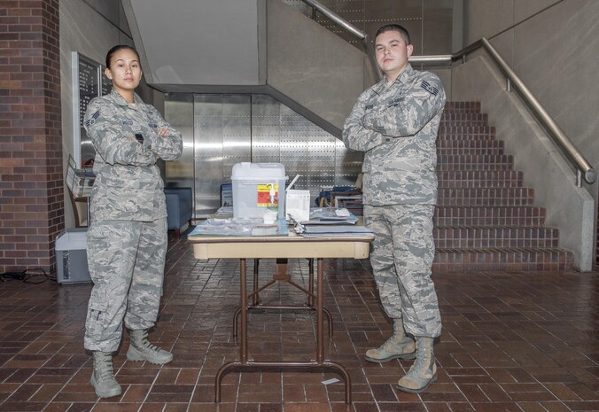 U.S. Air Force Senior Airman Cheree Voto, left, 628th Aerospace Medical Squadron immunization backup technician and U.S. Air Force Staff Sgt. Jacob Radford, right, 628th Aerospace Medical Squadron allergy and immunizations technician, wait to administer flu shots at a mobile flu line in the Joint Base Charleston Headquarters Building Nov. 7, 2017.