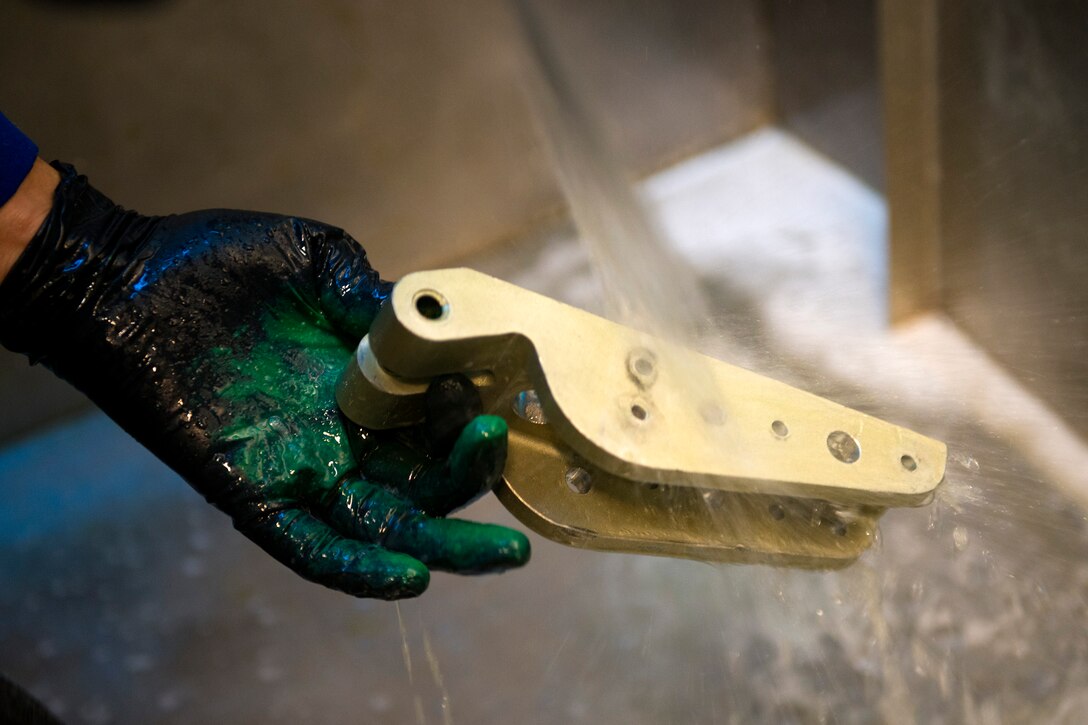 Senior Airman Joshua Sanchez, 23d Equipment Maintenance Squadron non-destructive inspection (NDI) technician, rinses off an aircraft part, Nov. 7, 2017, at Moody Air Force Base, Ga. NDI technicians use various techniques to inspect cracks or defects on aircraft parts, thereby preventing potentially catastrophic aircraft incidents. (U.S. Air Force photo by Airman 1st Class Erick Requadt)