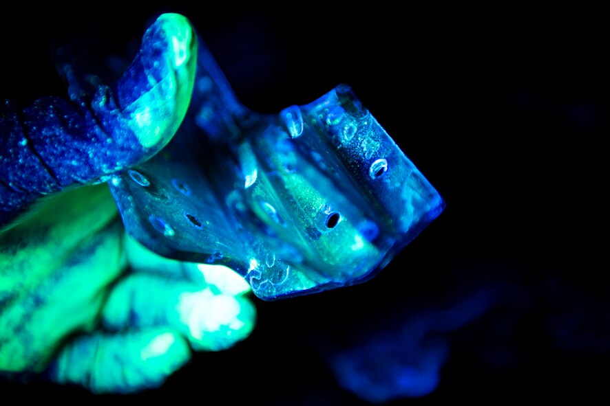Senior Airman Joshua Sanchez, 23d Equipment Maintenance Squadron non-destructive inspection (NDI) technician, examines an aircraft part using a florescent dye penetrant, Nov. 7, 2017, at Moody Air Force Base, Ga. NDI technicians use various techniques to inspect cracks or defects on aircraft parts, thereby preventing potentially catastrophic aircraft incidents. (U.S. Air Force photo by Airman 1st Class Erick Requadt)