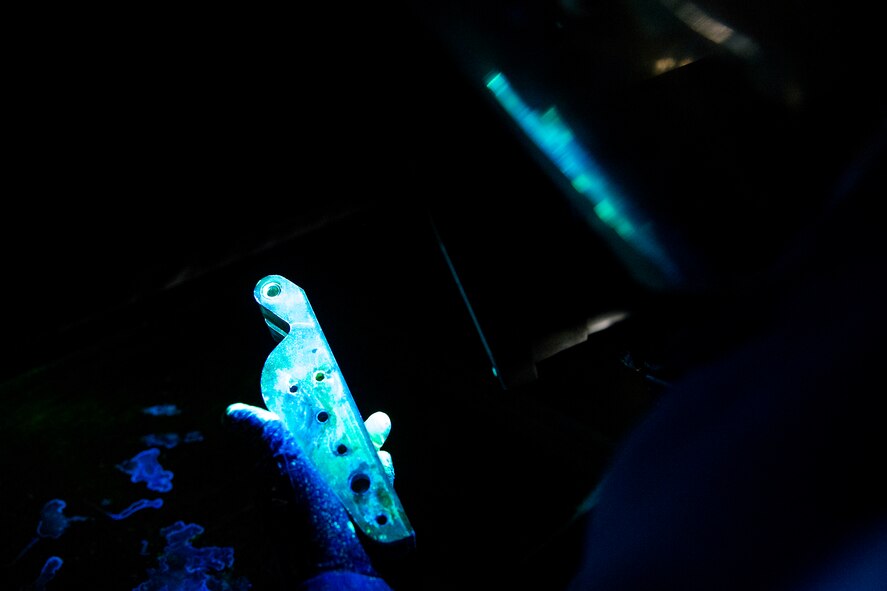 Senior Airman Joshua Sanchez, 23d Equipment Maintenance Squadron non-destructive inspection (NDI) technician, examines an aircraft part using a florescent dye penetrant, Nov. 7, 2017, at Moody Air Force Base, Ga. NDI technicians use various techniques to inspect cracks or defects on aircraft parts, thereby preventing potentially catastrophic aircraft incidents. (U.S. Air Force photo by Airman 1st Class Erick Requadt)