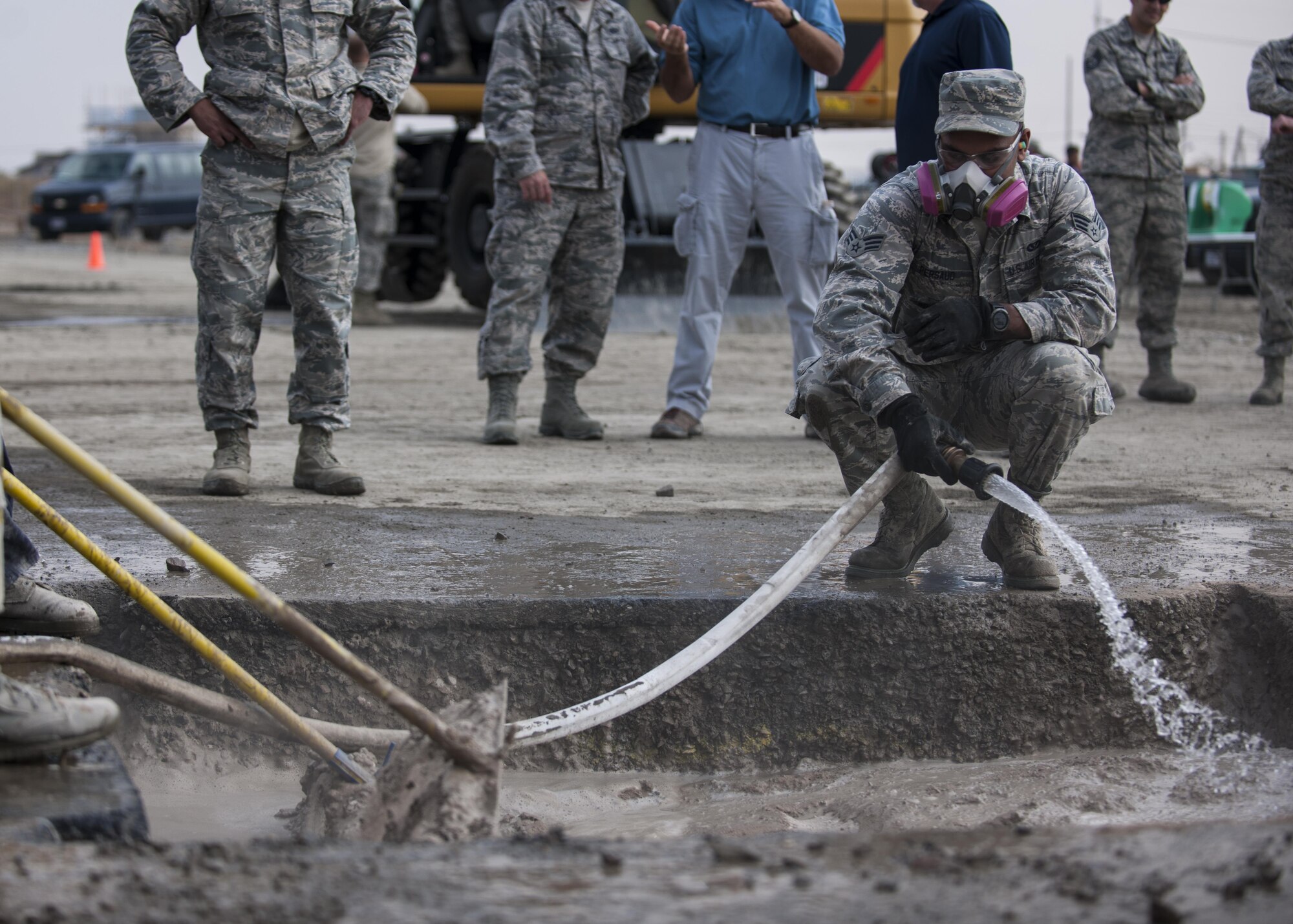 U.S. Air Force Senior Airman Sean Persaud, 8th Civil Engineer Squadron Water and Fuel Systems Maintenance journeyman, fills a damaged area with water while Airmen simultaneously mix in rapid-set concrete during rapid airfield damage repair training at Kunsan Air Base, Republic of Korea, Oct. 25, 2017. Members from the Air Force Civil Engineer Center, Tyndall Air Force Base, Fla., instructed Airmen assigned to the 8th CES on the new RADR process. (U.S. Air Force photo by Staff Sgt. Victoria H. Taylor)