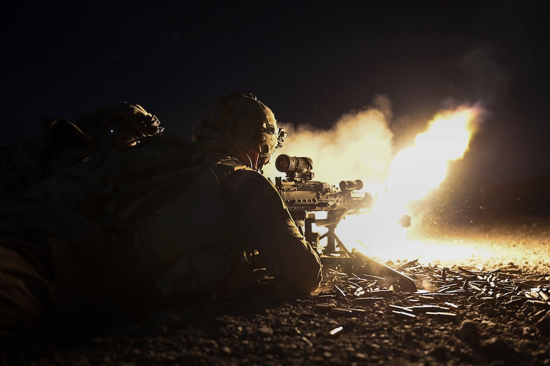 A soldier fires his M240 machine gun at night in Djibouti.