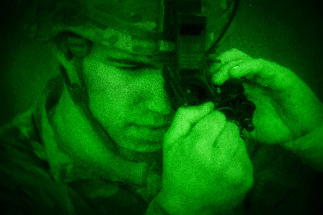 As seen through a night-vision device, a soldier adjusts his night vision goggles before firing his M240 machine gun in Djibouti.