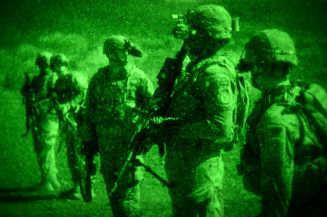 As seen through a night-vision device, soldiers wait for orders to take the firing line and fire M240 machine guns at night in Djibouti.