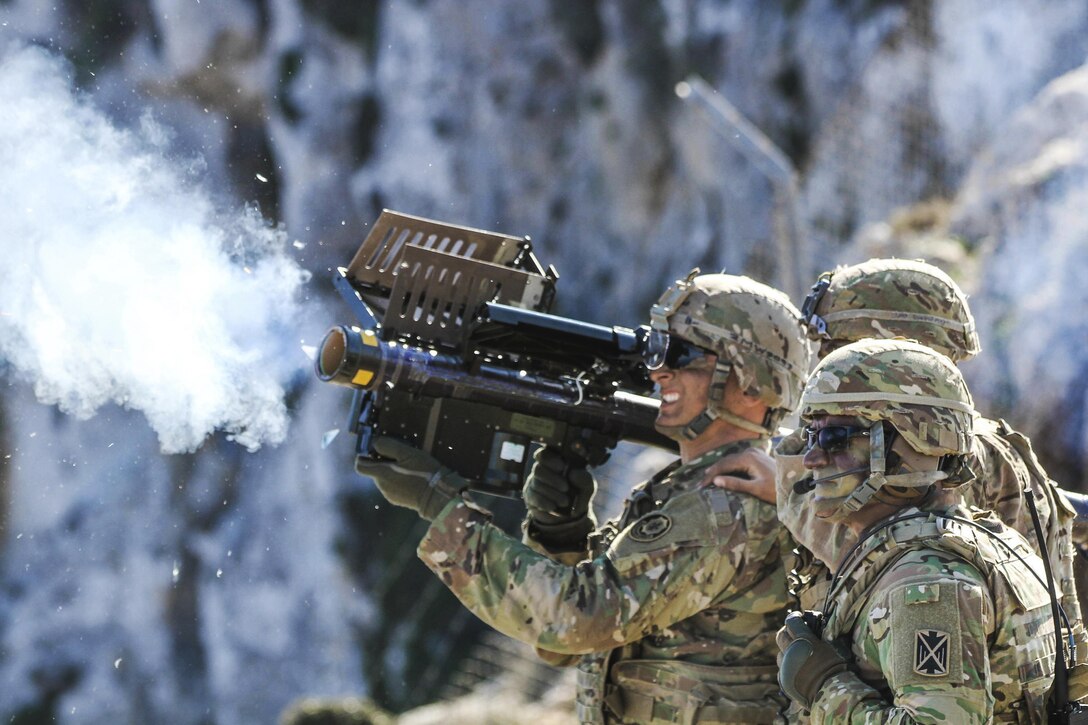 Three soldiers fire a shoulder mounted missile system.