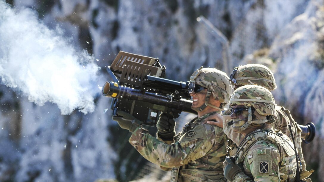 Three soldiers fire a shoulder mounted missile system.