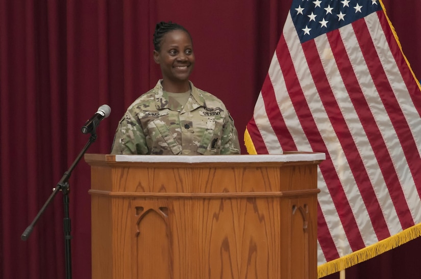 Female Soldier on stage at a podium.