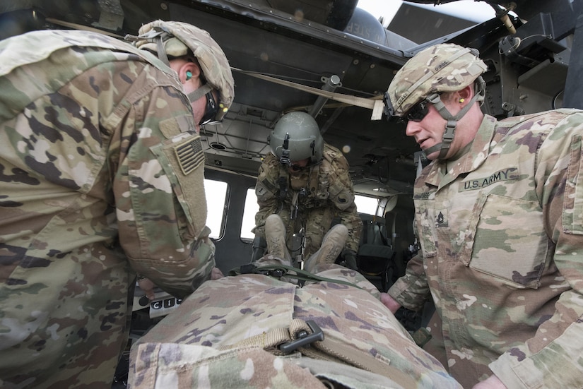 Soldiers load another Soldier on a litter into a helicopter.