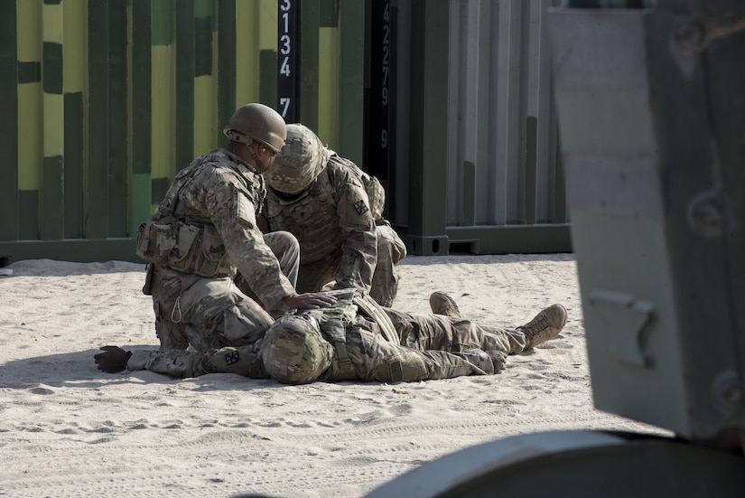 Two Soldiers practice lifesaving skills on a simulated casualty.