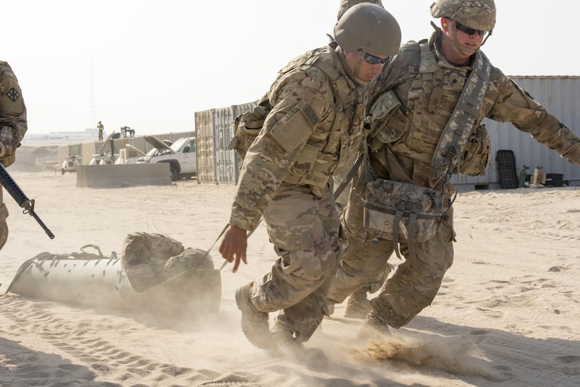 Two Soldiers drag a simulated casualty on a litter.