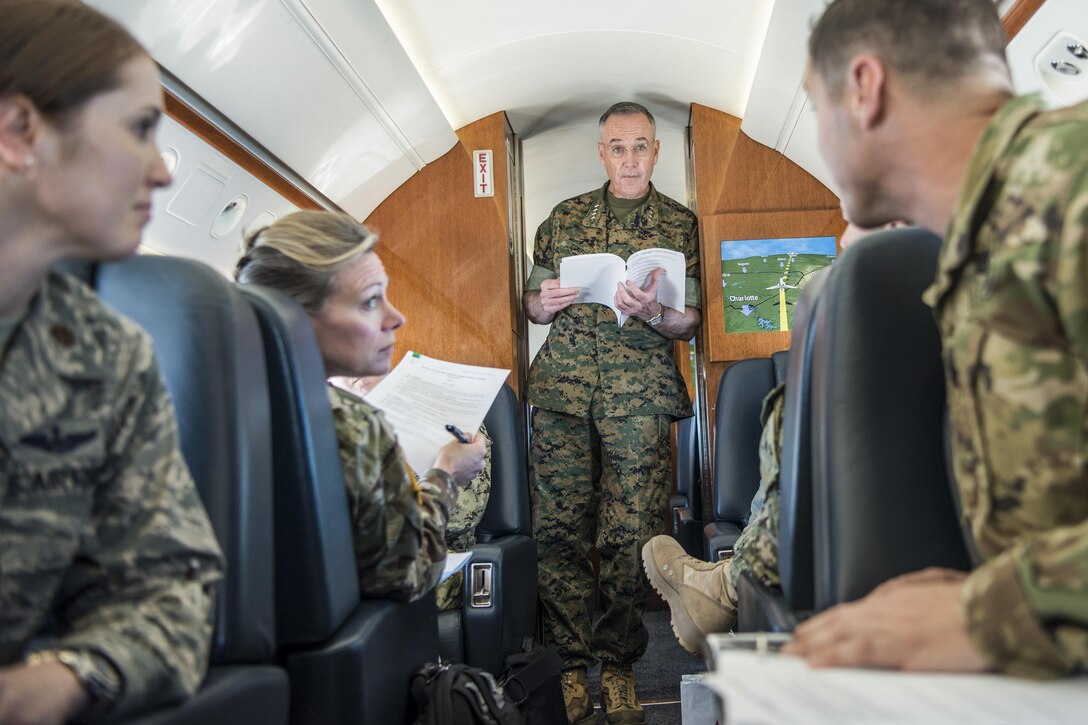 The chairman of the Joint Chiefs of Staff meets with his staff on an aircraft.