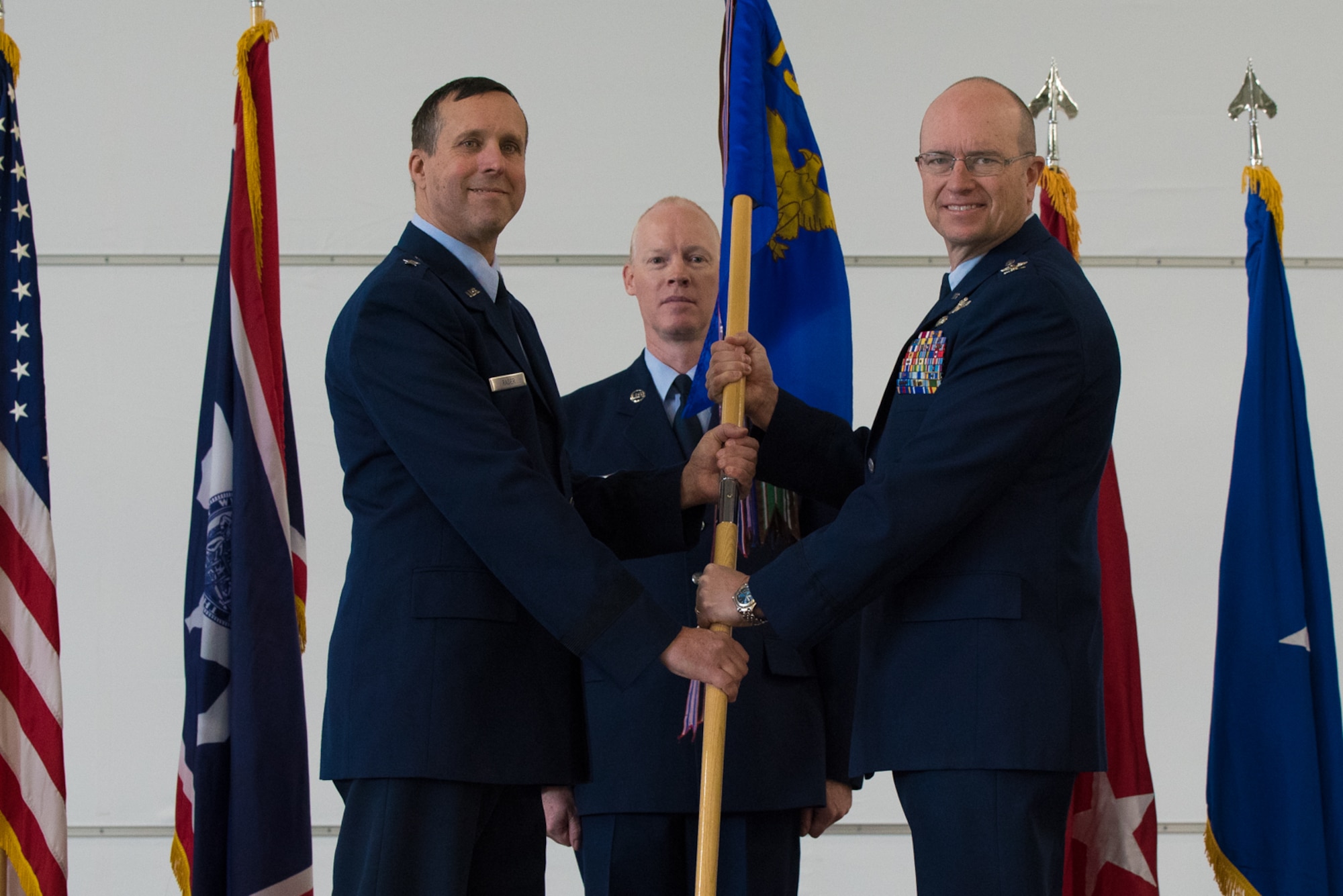 U.S. Air Force Brig. Stephen Rader passes the 153rd Airlift Wing guidon to incoming commander Col. Justin Walrath.