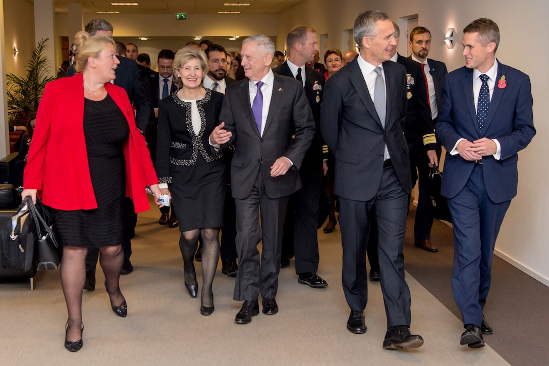 Defense leaders walk down a hallway at NATO headquarters.