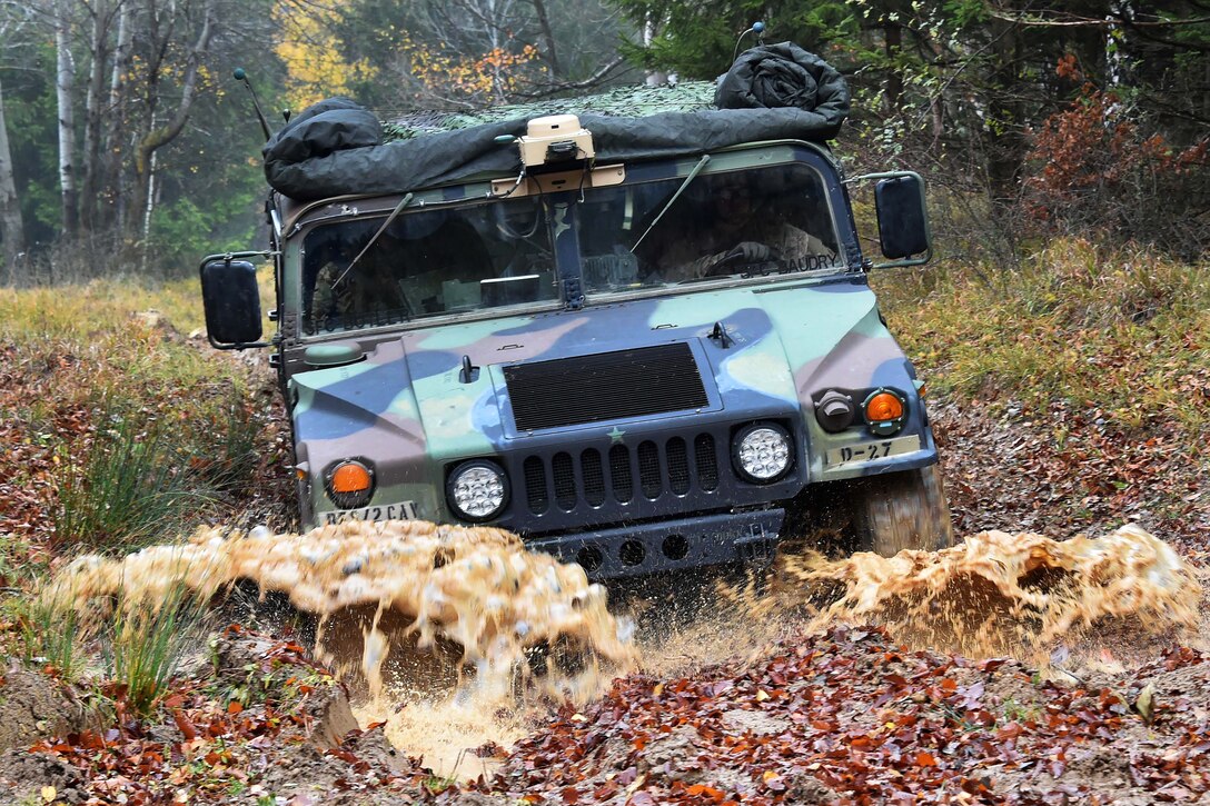 A humvee splashes in the mud.