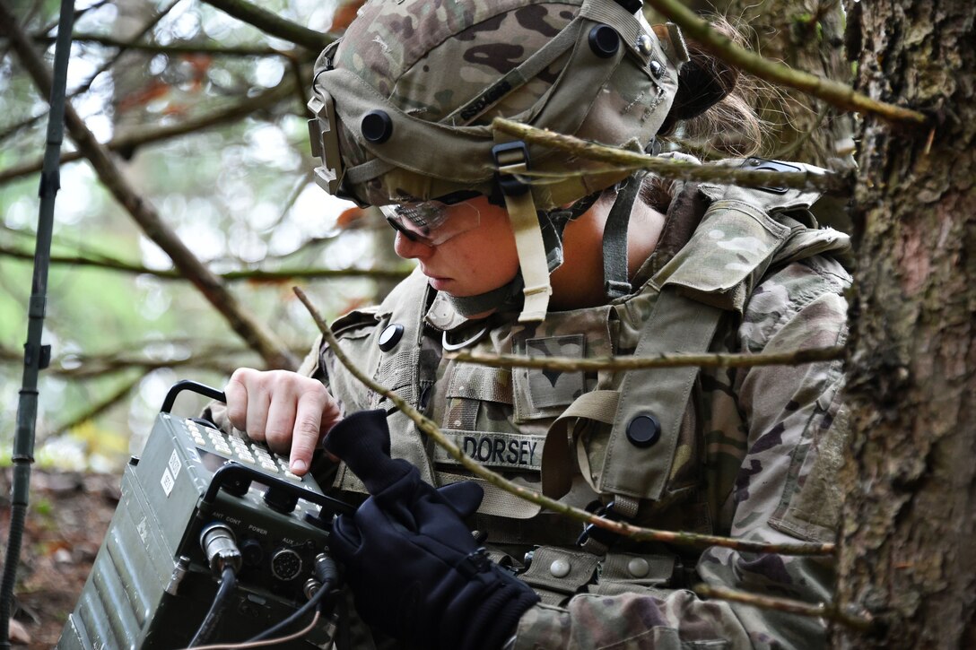 A soldier on the ground uses portable electronic equipment.