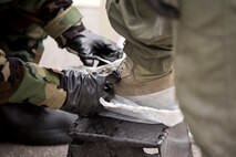 U.S. Air Force Reserve Staff Sgt. Michael Richardson, flight equipment technician, 327th Operations Support Squadron, cuts the laces from an aircrew member’s boot during a decontamination simulation Nov. 4, 2017, at Little Rock Air Force Base, Ark.