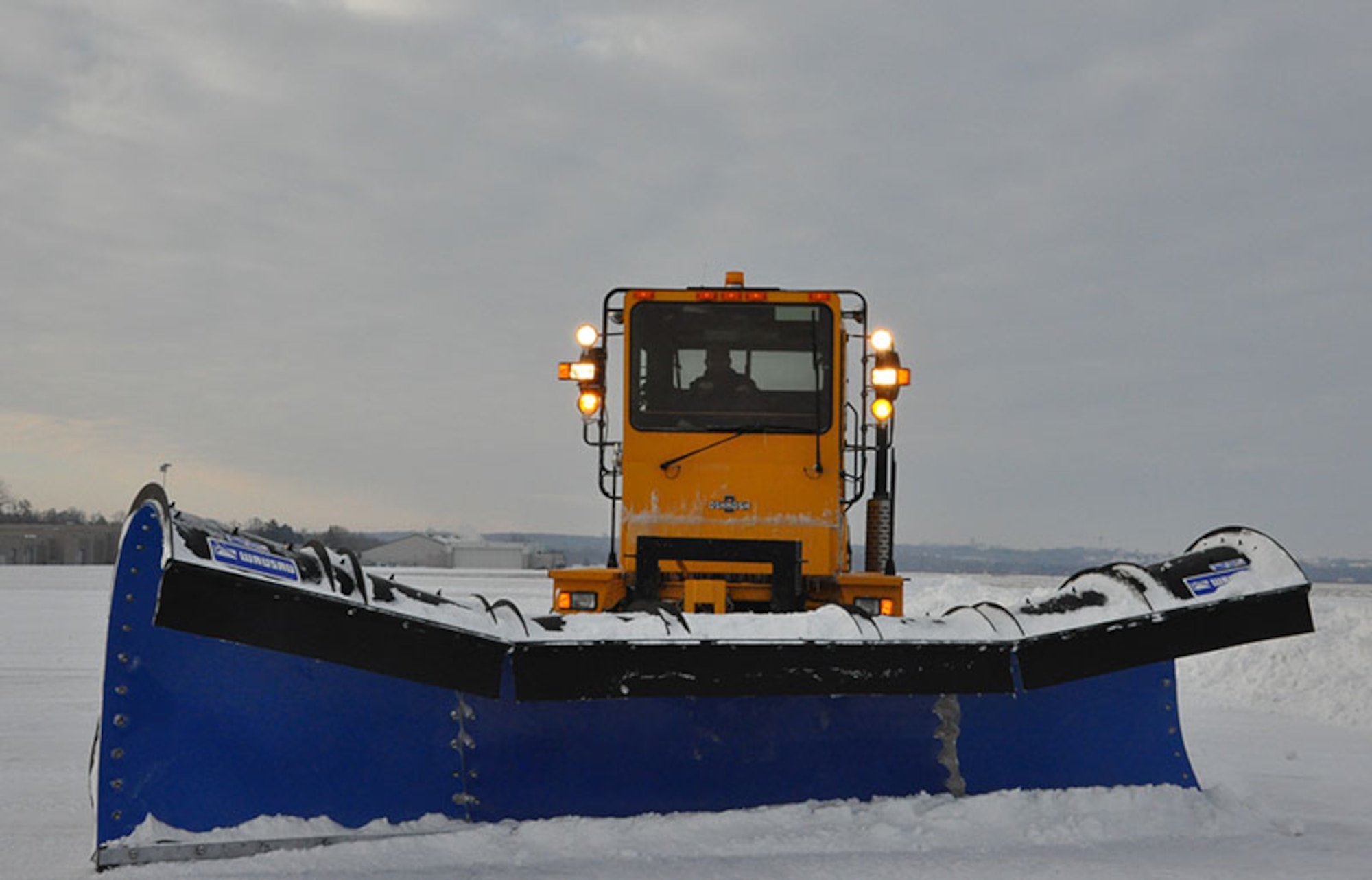A snow plow clears the runway at Wright-Patterson AFB. Severe weather events like a snow storm can wreak havoc on runways and streets on the installation, causing reporting delays or base closures. (U.S. Air Force photo)