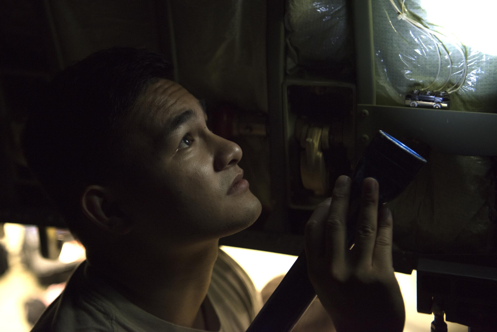 U.S. Air Force Senior Airman Joshua Dayrit, 86th Aircraft Maintenance Squadron C-130J Super Hercules crew chief, shines a flashlight at a broken aircraft part on Ramstein Air Base, Germany, Oct. 13, 2017. Crew chiefs are responsible for general maintenance and repairs on aircraft. (U.S. Air Force photo by Airman 1st Class Devin M. Rumbaugh)