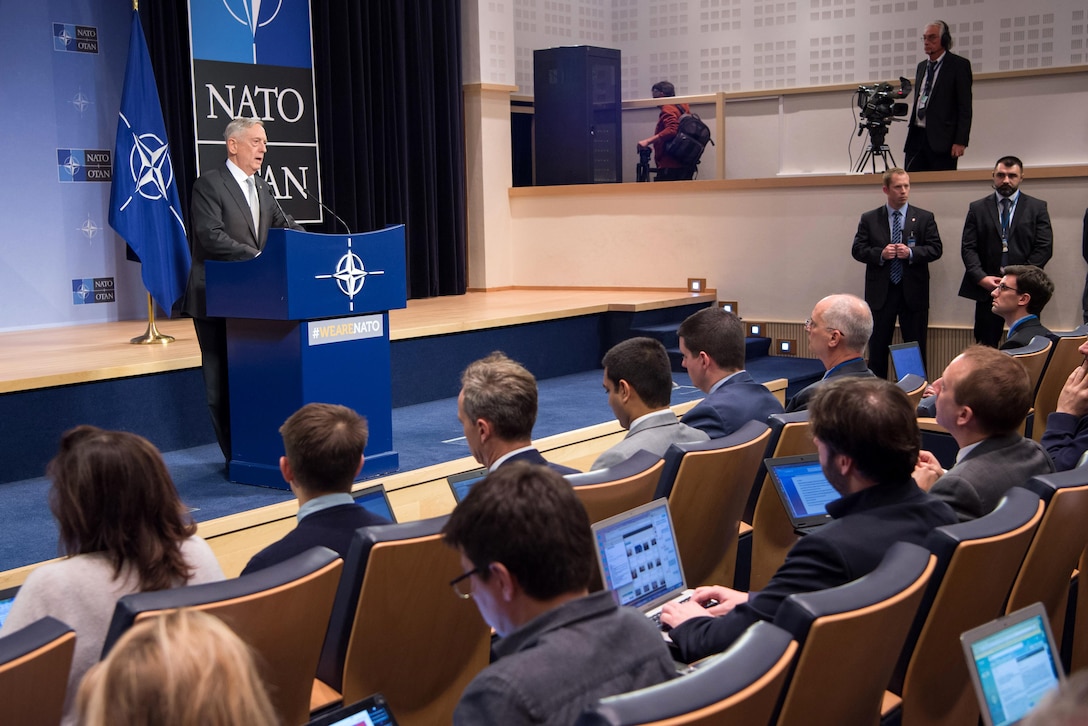 Defense Secretary Jim Mattis speaks from behind a podium to a group of people.