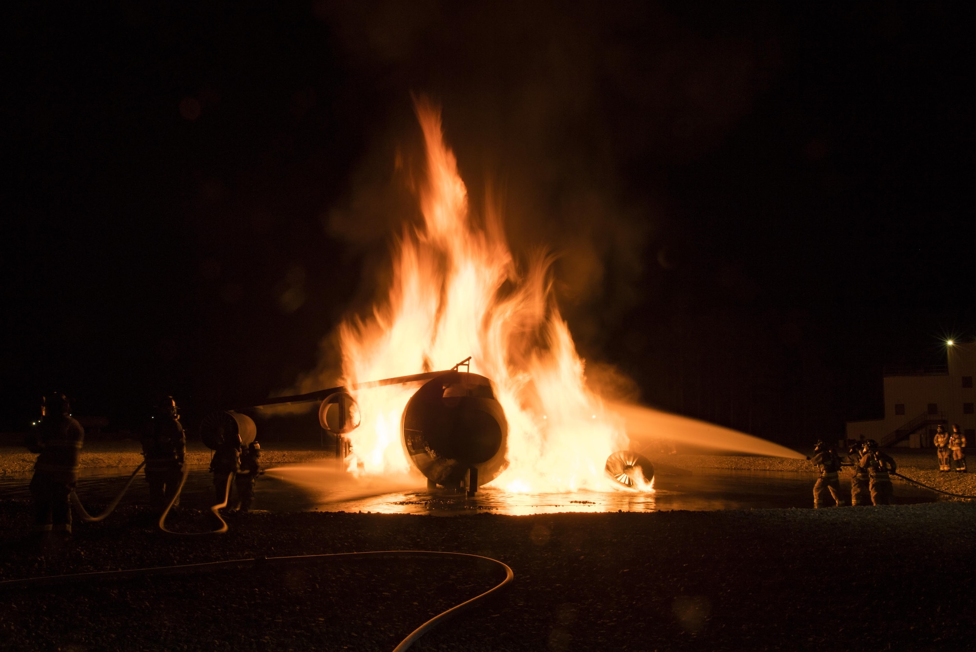 Flames rise from a prop aircraft as firefighters douse it with water during nighttime live-fire training, Nov. 8, 2017, at Moody Air Force Base, Ga. This training is an annual requirement for Moody firefighters and is just one of the ways they stay ready to protect people, property and the environment from fires and disasters. (U.S. Air Force photo by Senior Airman Janiqua P. Robinson)