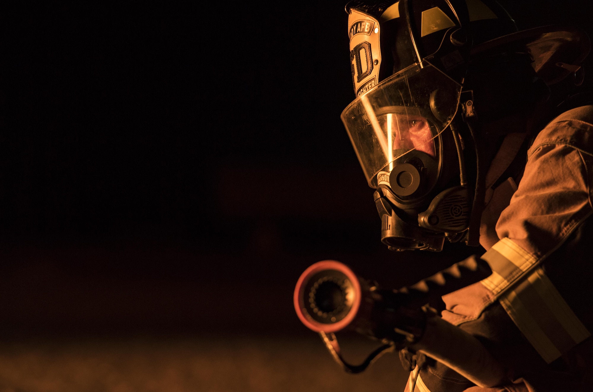 A firefighter from the 23d Civil Engineer Squadron watches his colleagues put out a fire during nighttime live-fire training, Nov. 9, 2017, at Moody Air Force Base, Ga. Moody and the Valdosta Fire Department joined forces to prepare for the possibility of nighttime aircraft fire operations. (U.S. Air Force photo by Senior Airman Janiqua P. Robinson)