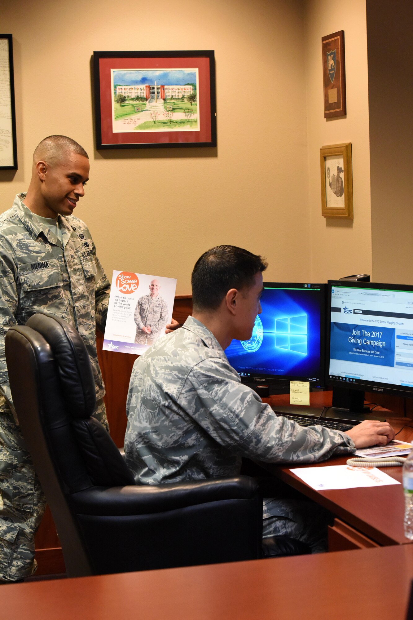 U.S. Air Force Staff Sgt. Eric Medina, 17th Force Support Squadron manpower analyst, and Col. Ricky Mills, 17th Training Wing commander, look at the Combined Federal Campaign website to sign up for this year’s campaign at the Norma Brown building on Goodfellow Air Force Base, Texas, Nov. 8, 2017. The base’s goal for the campaign this year is to raise 87 thousand dollars for charity. (U.S. Air Force photo by Airman 1st Class Seraiah Hines/Released)