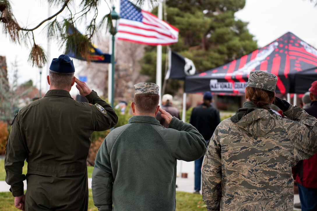 National Guardsmen salute during the National Anthem at a Veterans Day ceremony.