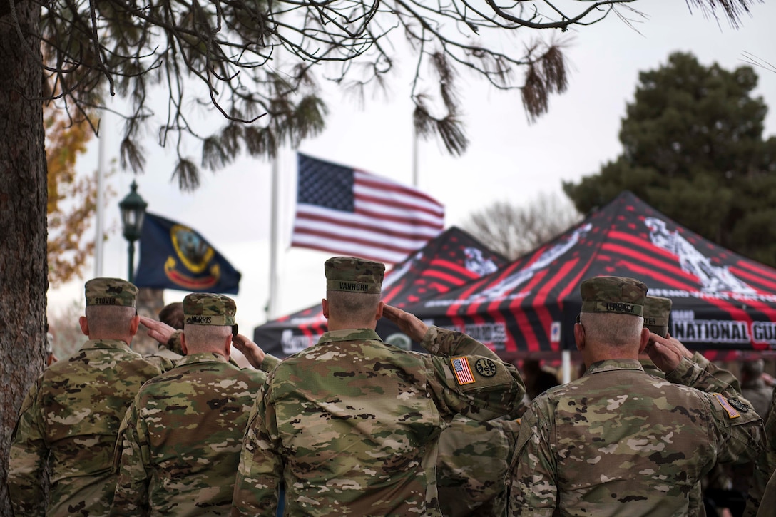 National Guardsmen salute during the National Anthem at a Veterans Day ceremony.