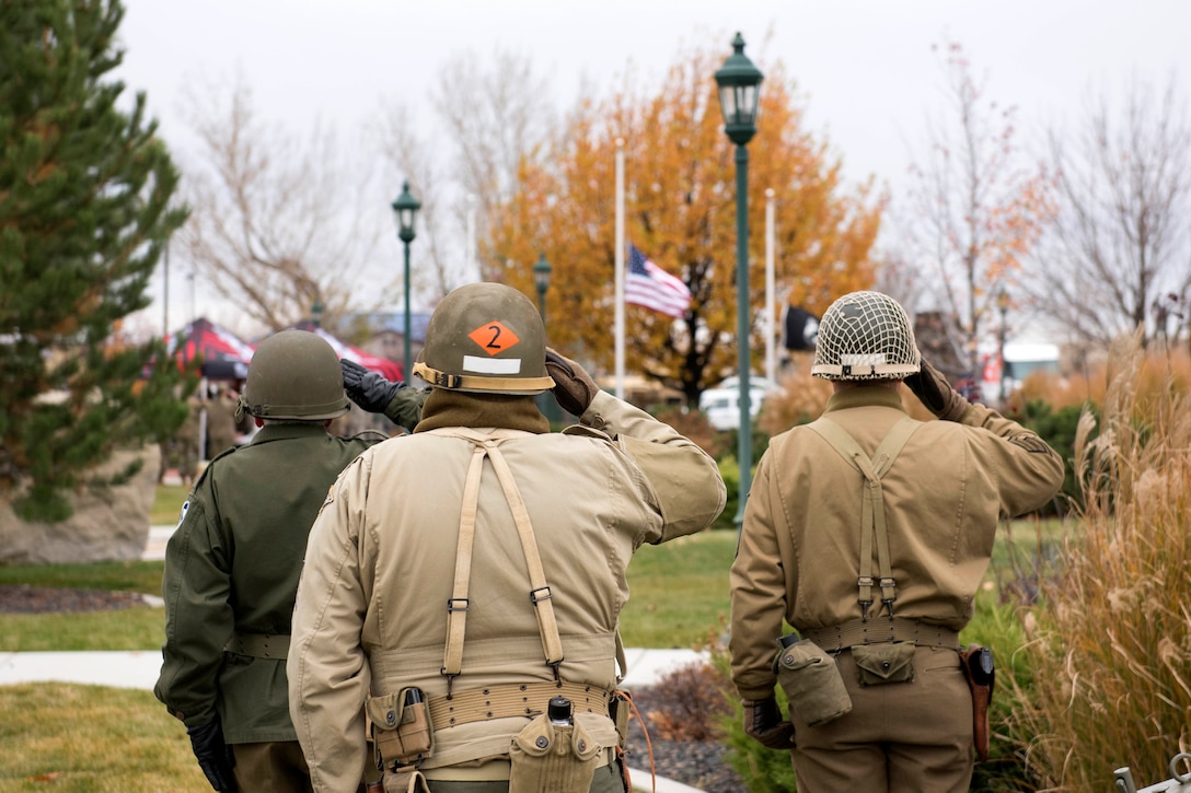 Idaho Army National Guardsmen role-playing as WW II soldiers salute during a Veterans Day ceremony.