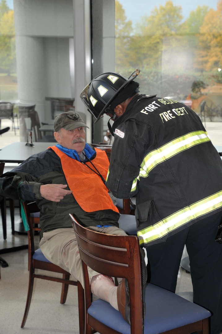 Firefighter standing over actor/'victim' rendering aid