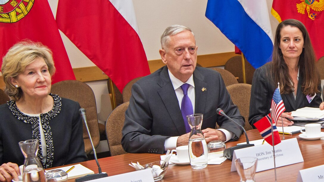 Defense Secretary Jim Mattis sits at a table next to two women on either side.