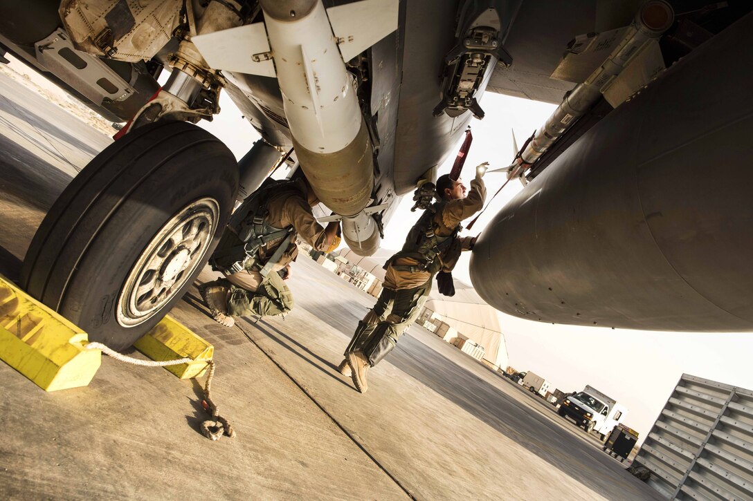 Air Force airmen perform pre-flight checks on an F-15E Strike Eagle aircraft before a sortie.